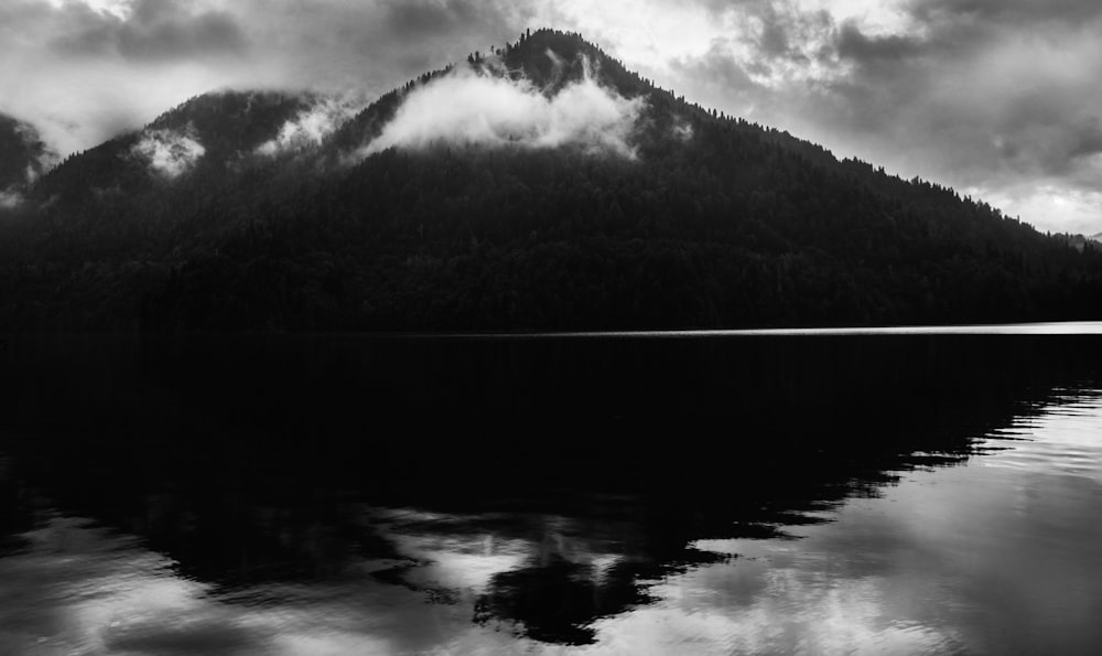 a black and white photo of a mountain with clouds