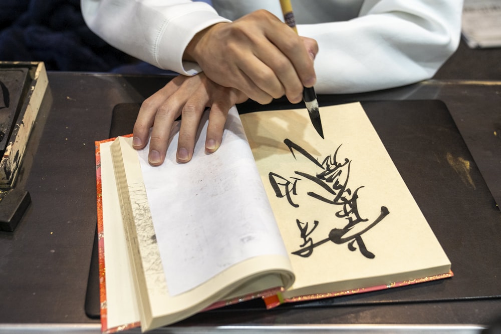 uma pessoa com uma caneta escrevendo em um livro