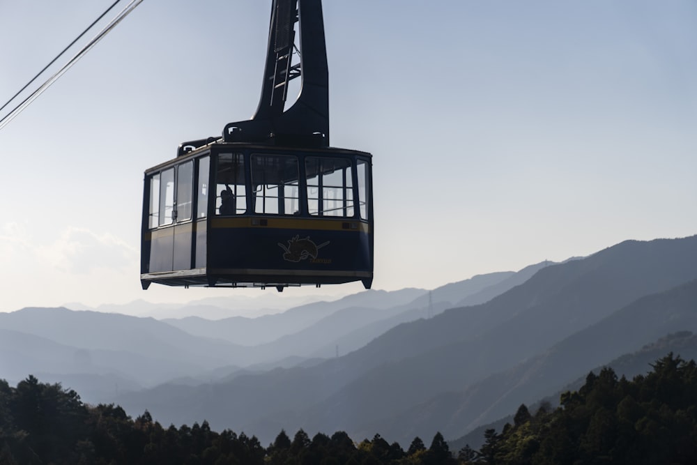 eine Seilbahn, die auf einen Berg mit Bergen im Hintergrund fährt