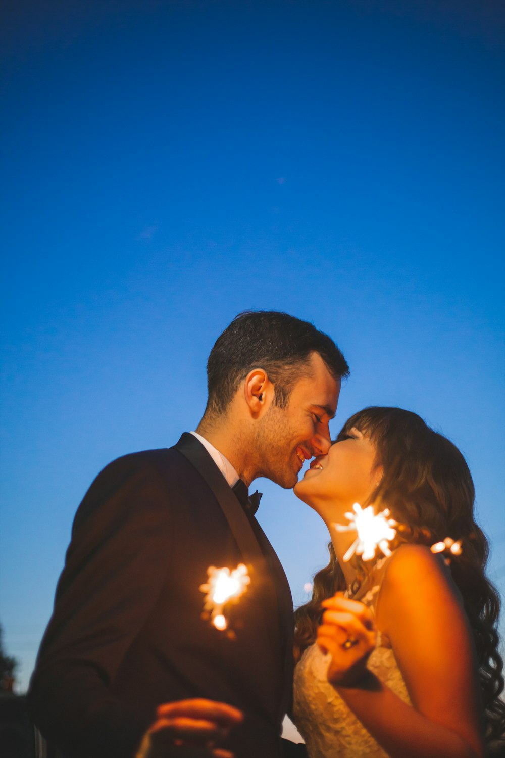 a man and a woman kissing while holding sparklers