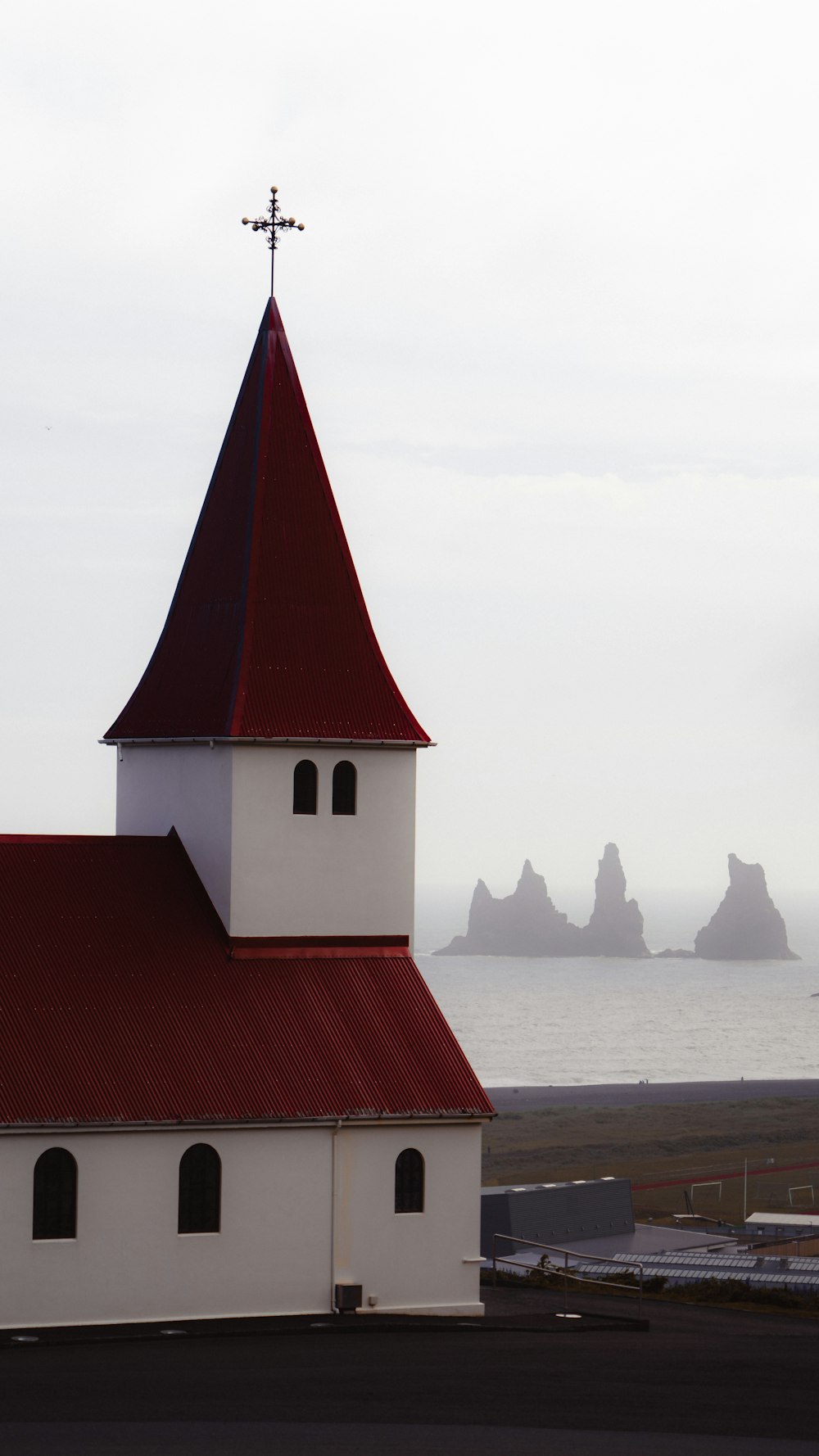 a white church with a red roof next to a body of water