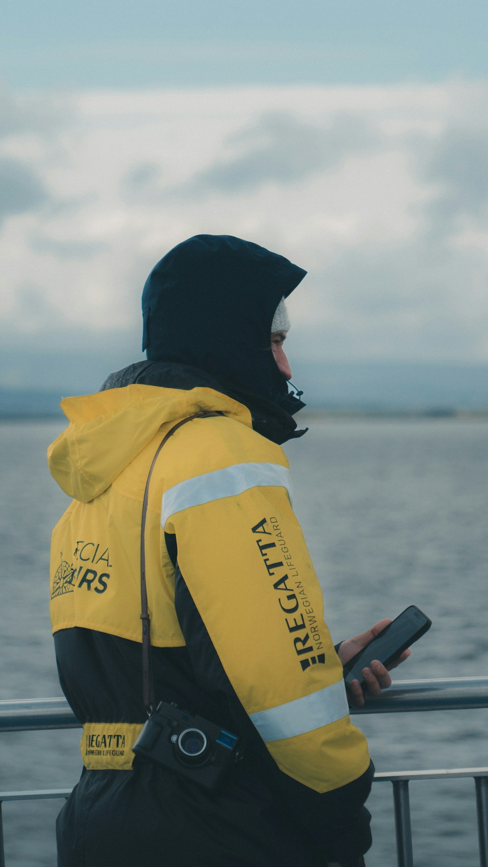 a man in a yellow jacket looking at a cell phone