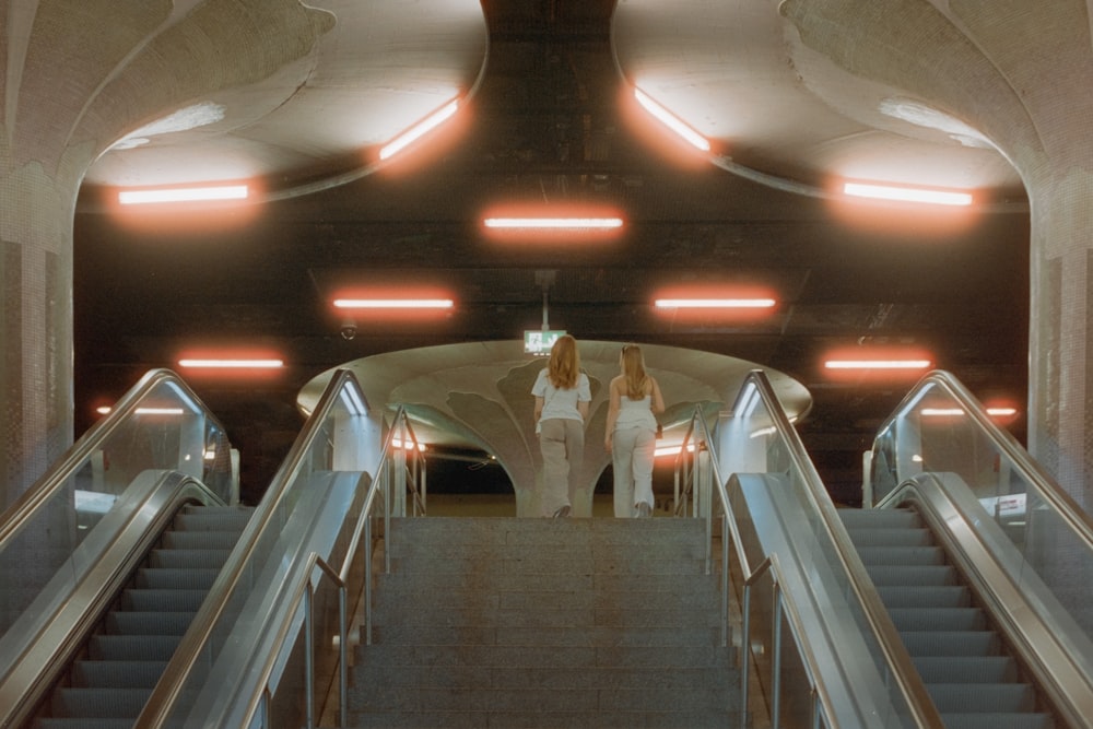 a couple of women walking down an escalator