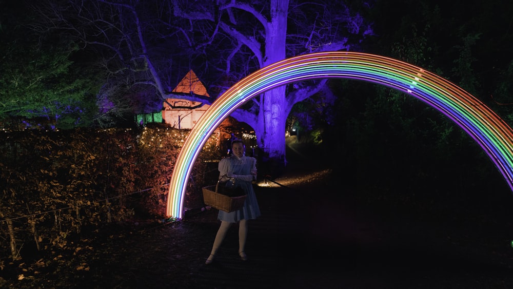 a woman holding a basket standing in front of a rainbow arch