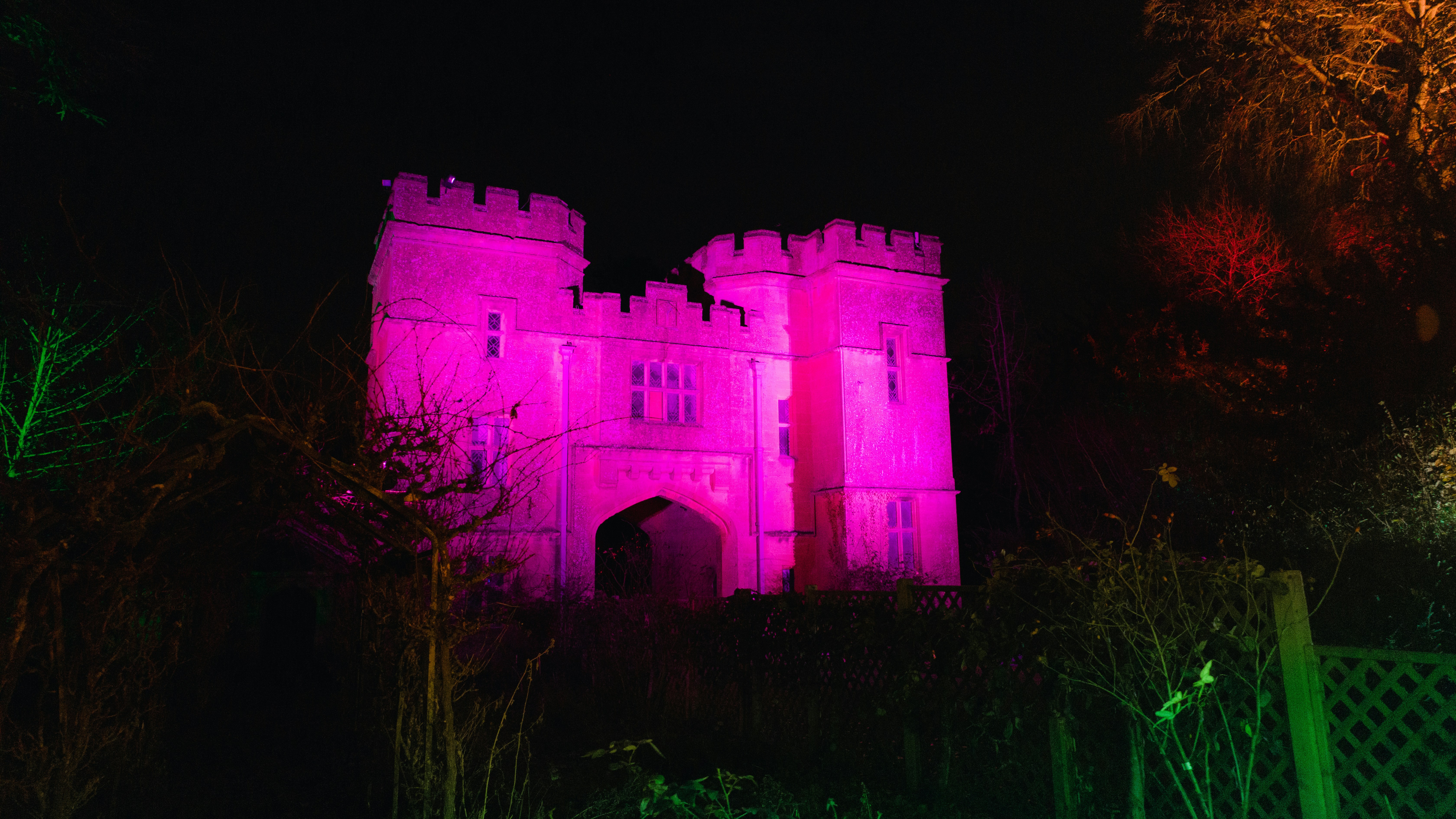 Un castillo iluminado de rosa por la noche