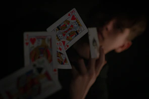 The fucking magician casting eerie shadows with twisted cards under flickering lights.