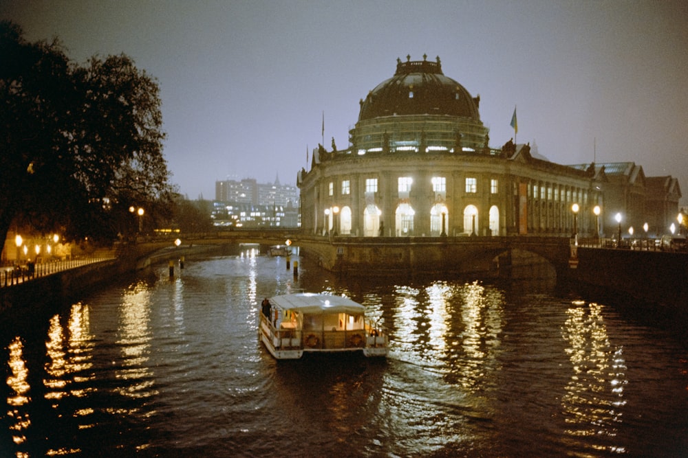 a boat traveling down a river next to a large building