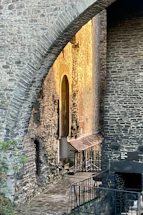A sunlit historic stone archway inviting visitors to step inside.