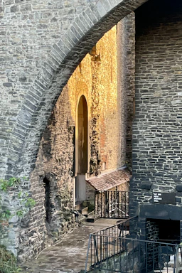 A sunlit historic stone archway inviting visitors to step inside.