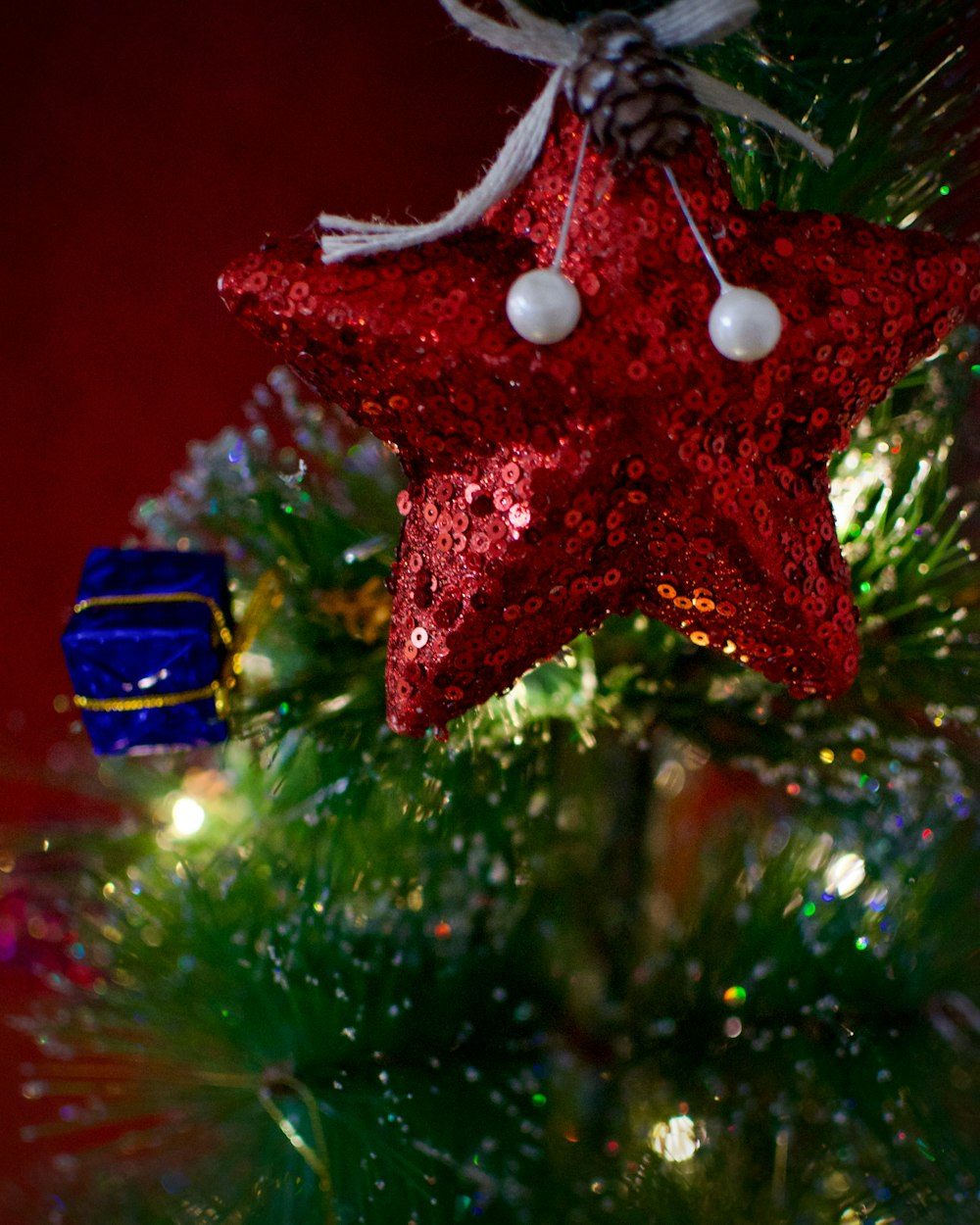a red star ornament hanging from a christmas tree