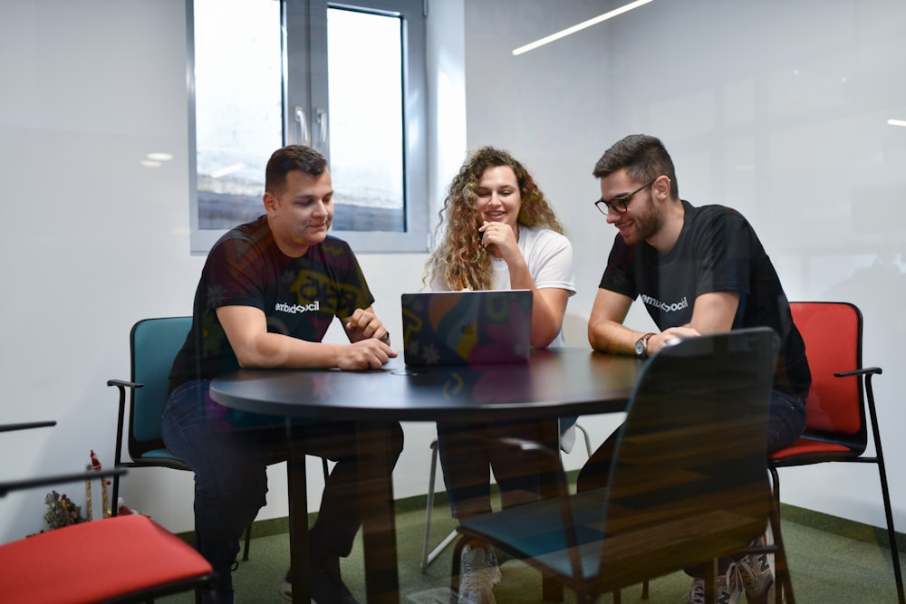 a group of people sitting around a table with laptops