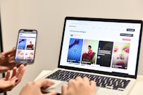 a person holding a cell phone next to a laptop