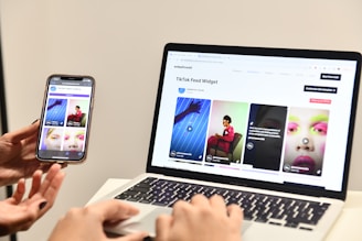 a person holding a cell phone next to a laptop