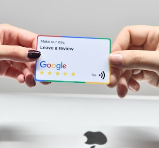 two hands holding a google credit card in front of an apple logo