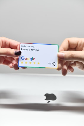 two hands holding a google credit card in front of an apple logo