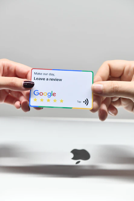 two hands holding a google credit card above an apple logo