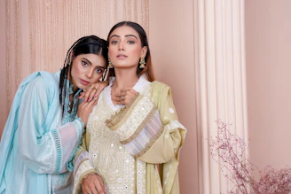 two women standing next to each other in front of a wall