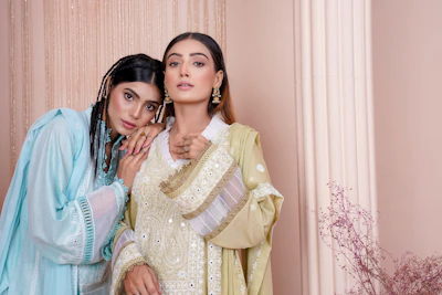 two women standing next to each other in front of a wall