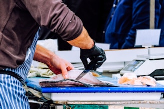 Artisan carefully slicing a large fish with precision in a bright, clean workspace.