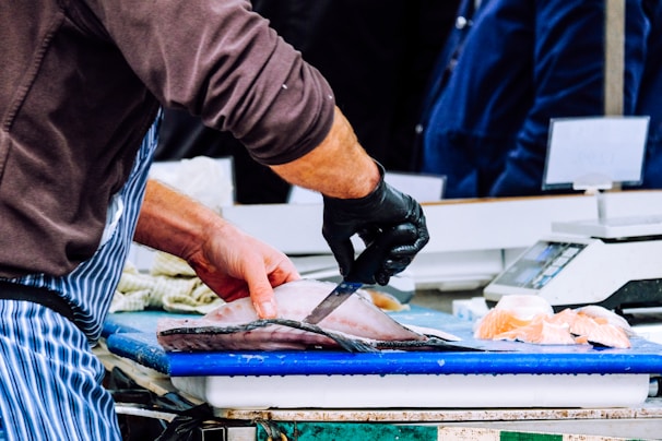 Artisan carefully slicing a large fish with precision in a bright, clean workspace.