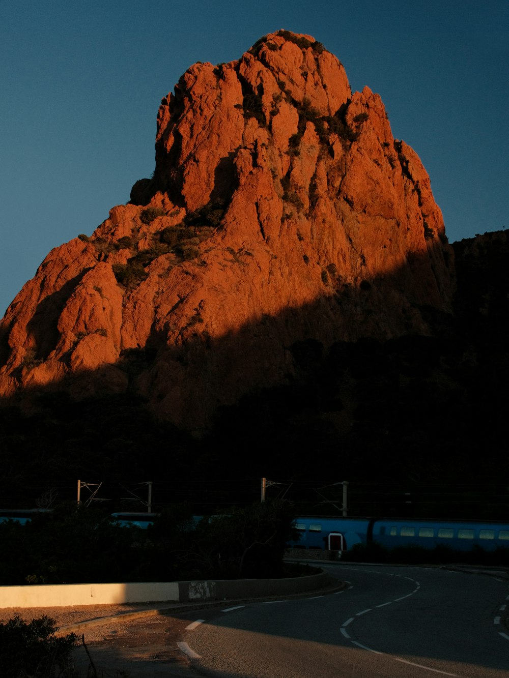 the sun is setting on a mountain with a train passing by