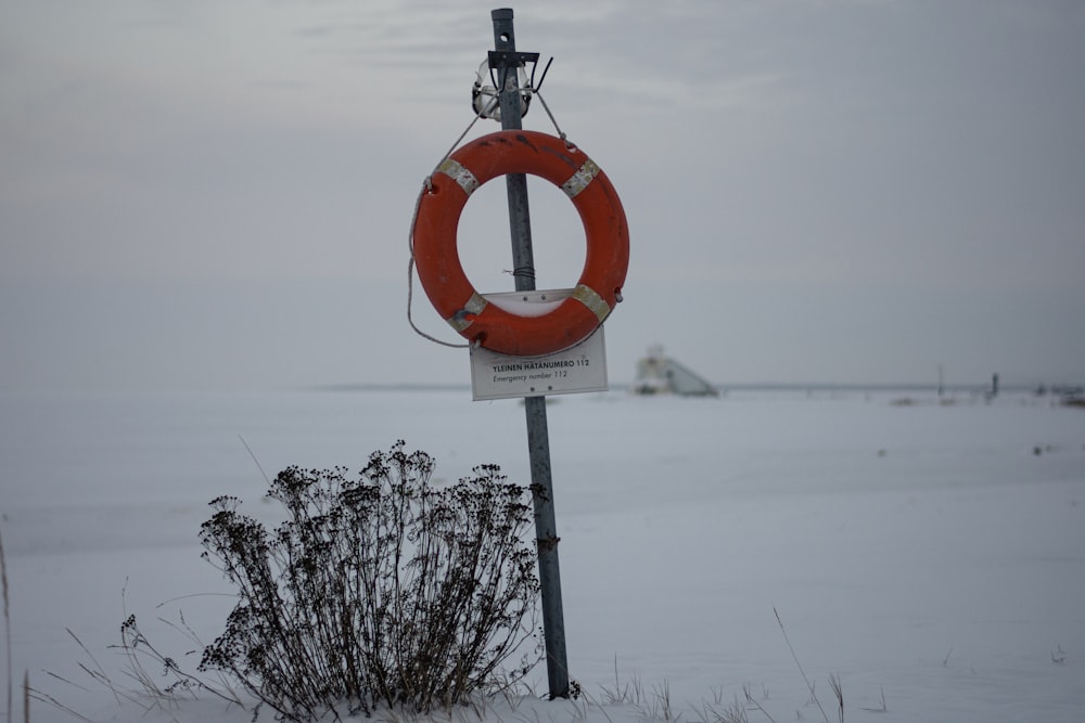 a life preserver sign on a pole in the snow