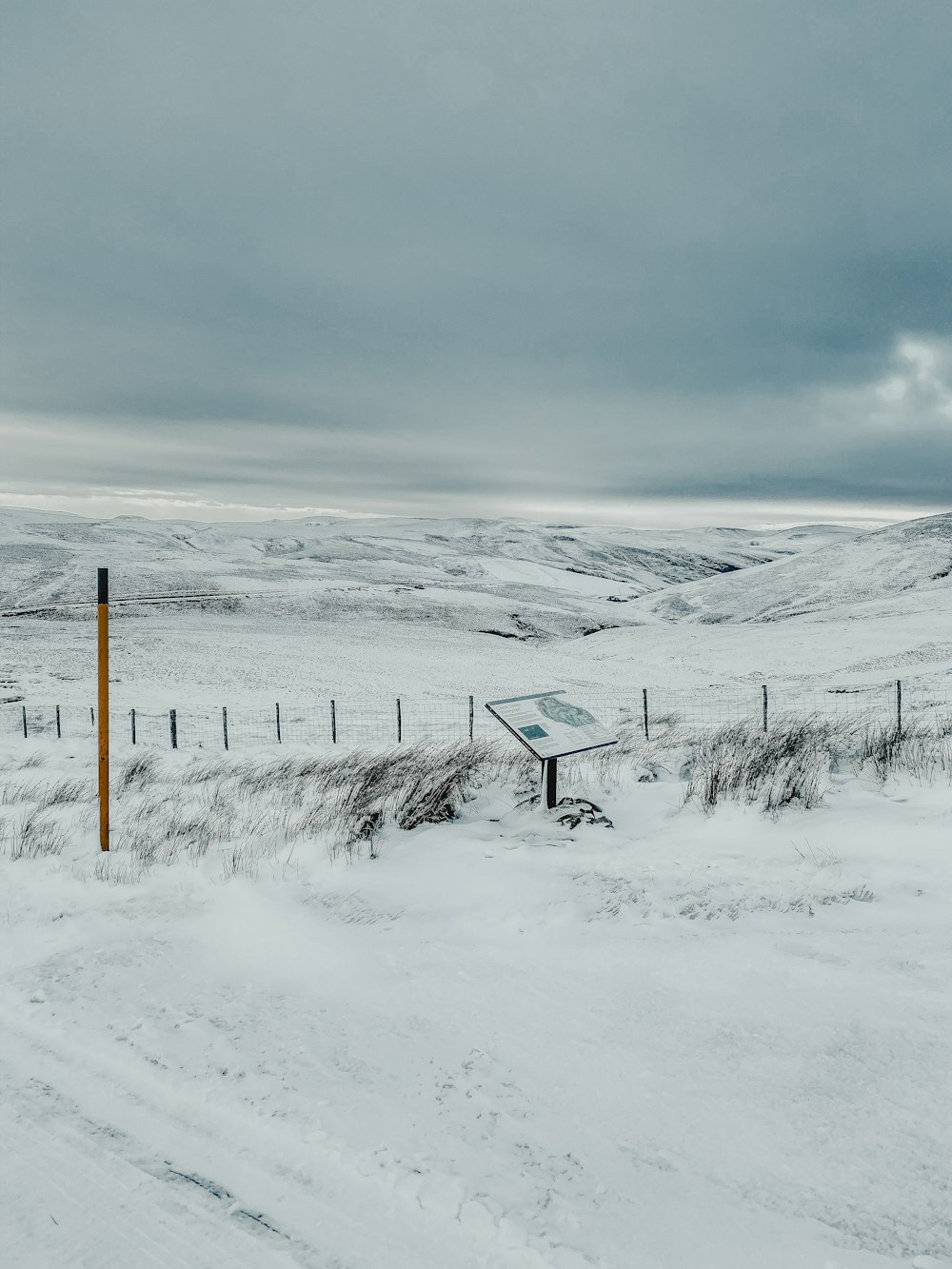 a snow covered field with a sign in the middle of it