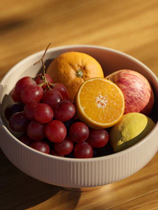 Close-up of a textured stoneware bowl in warm earthy tones, filled with fresh fruit
