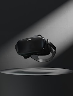 A virtual reality headset floating above a circular platform is illuminated by a spotlight. The surrounding area is dark, highlighting the sleek design of the device.