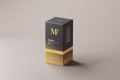 A sleek rectangular box with a minimalist design, primarily in black and gold. The box features bold typography with the initials 'MF' at the top and the text 'Sleek + Dropper Bottle Box Mockups' below. The design is clean and modern, with a soft shadow cast on the neutral background.