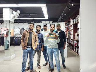 A group of friends trying on outfits in a fitting room.