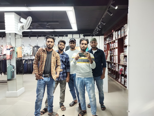 A group of friends trying on outfits in a fitting room.