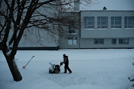 Close-up of a worker shoveling a walkway surrounded by fresh snow.