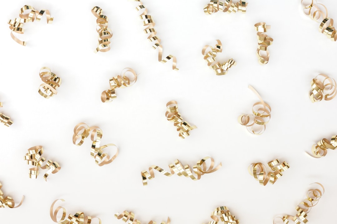 A close-up shot of various gold jewelry pieces (rings, necklaces) shimmering under soft light.