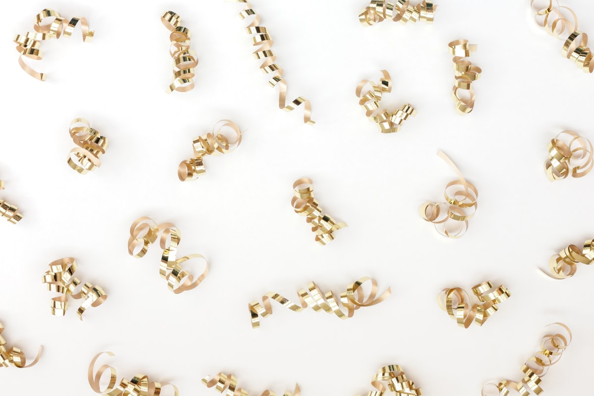 Gold jewelry pieces on white surface representing demi fine jewelry quality and everyday wearability for modern minimalist style