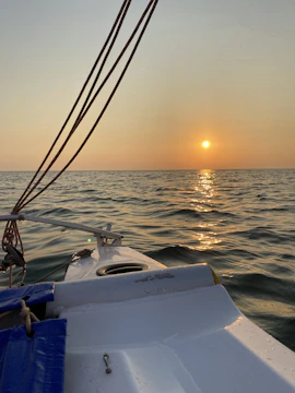 Golden hour shot of a family laughing aboard a sailboat, with soft-focus ropes and sails.