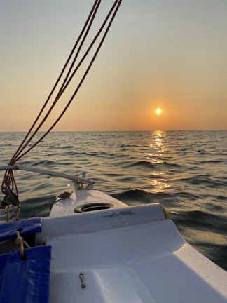 Evening shot of a tailored District Beach jacket draped over a sailboat railing with a golden sunset backdrop.