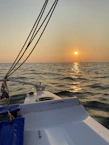 Captain Ravi smiling on his boat with the sunset over the Arabian Sea in the background.