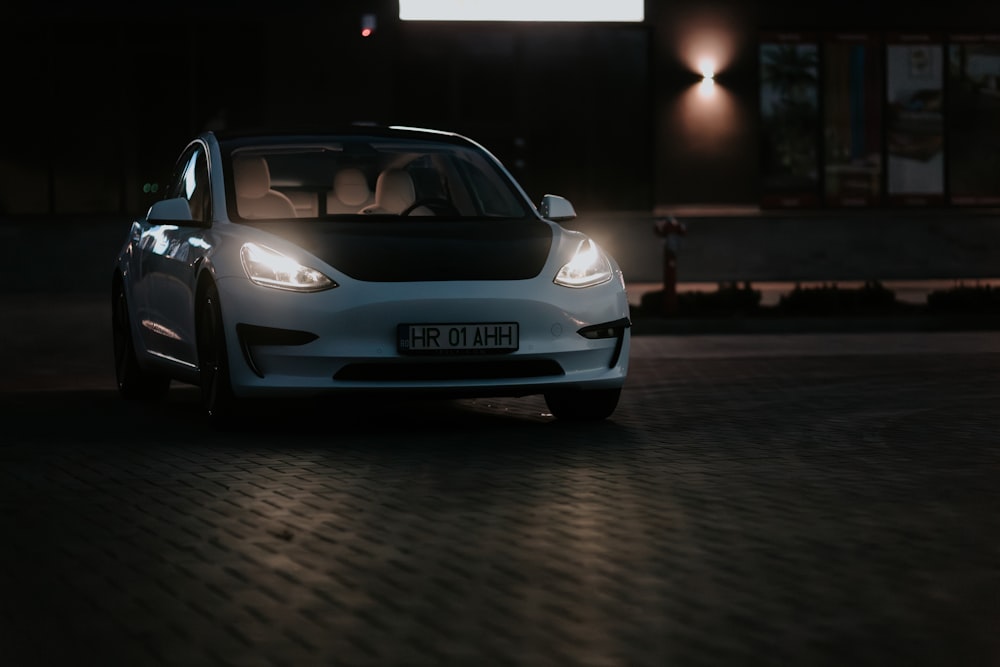 a white car parked in front of a building at night