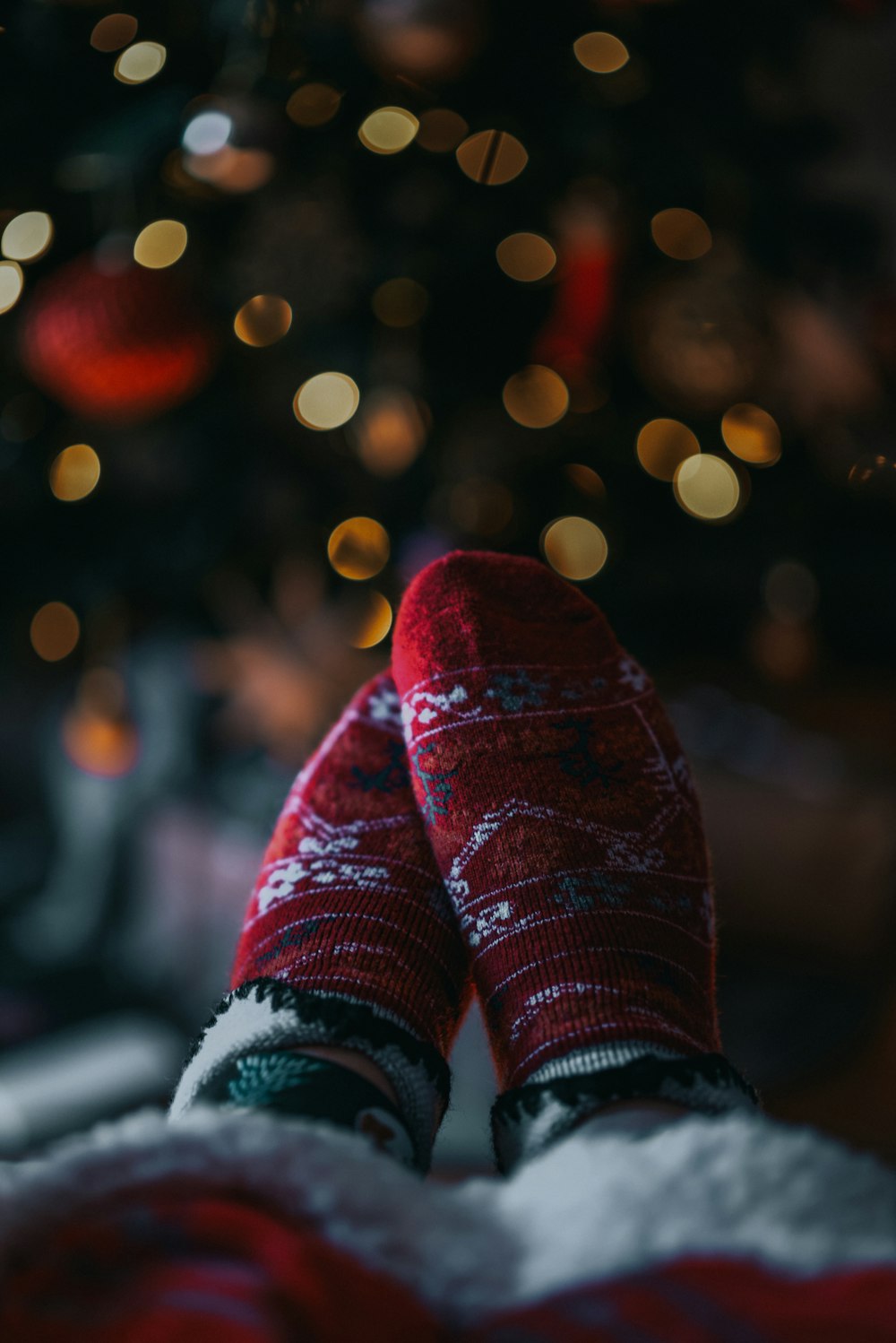 a person's feet with red socks and a christmas tree in the background