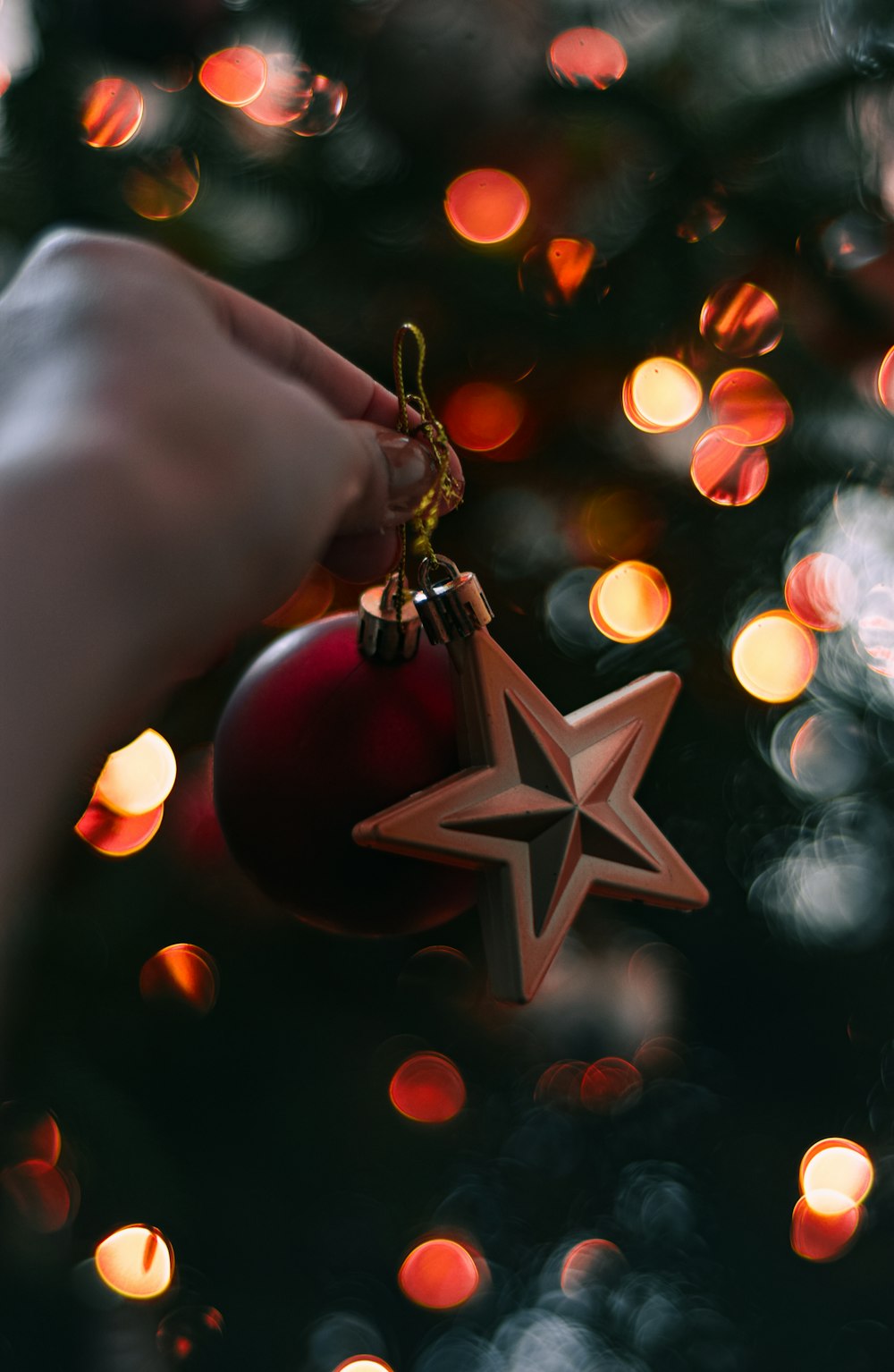 a hand holding a christmas ornament in front of a christmas tree