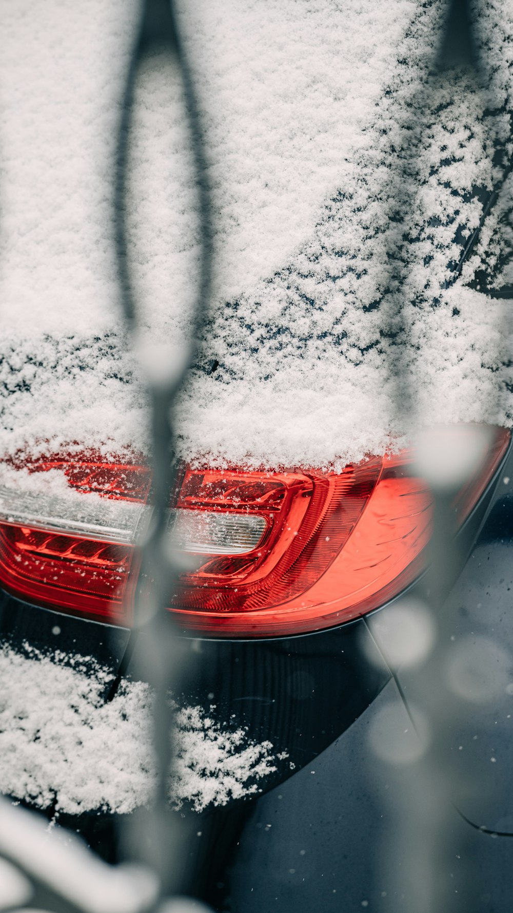 a car is covered in snow with a red tail light