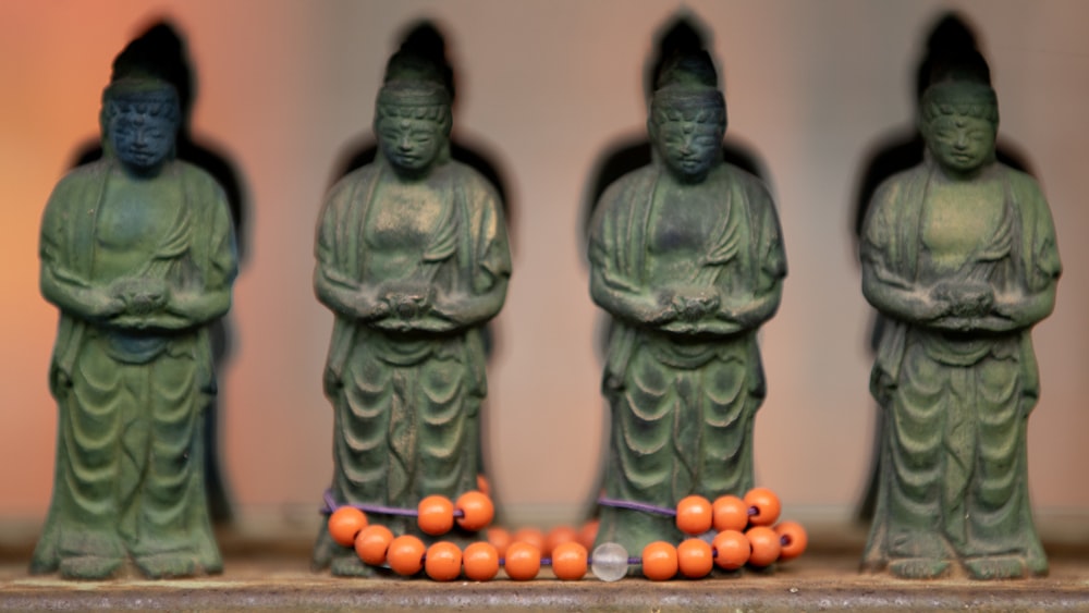 un gruppo di statue con palline arancioni davanti a loro