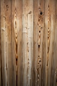 Vertical wooden planks with distinct grain patterns and knots, featuring a natural and rustic appearance.