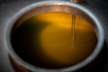 The image features a close-up view of a metallic container filled with a yellow liquid. Two thin metal rods are submerged into the liquid, which seems to be illuminated.