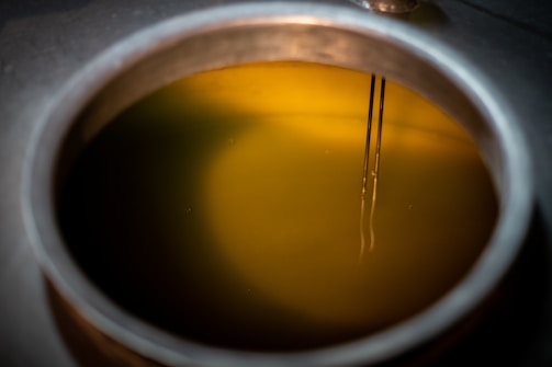The image features a close-up view of a metallic container filled with a yellow liquid. Two thin metal rods are submerged into the liquid, which seems to be illuminated.