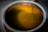The image features a close-up view of a metallic container filled with a yellow liquid. Two thin metal rods are submerged into the liquid, which seems to be illuminated.
