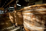Close-up of wooden fermentation barrels with koji rice inside, softly lit.