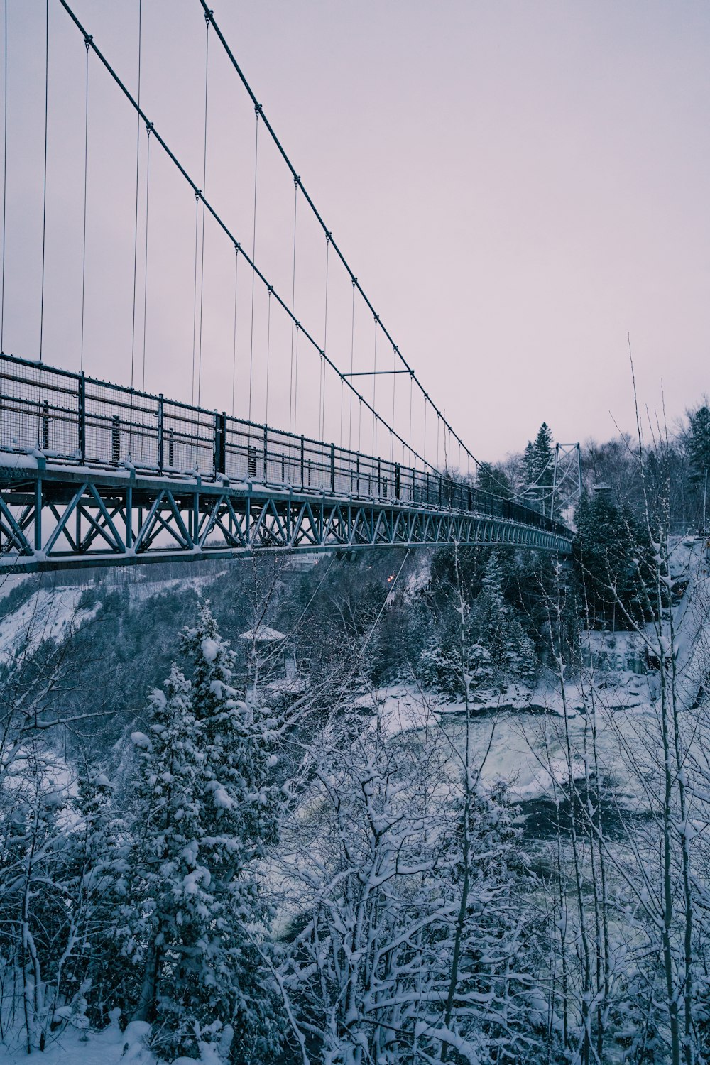 a suspension bridge over a river in the winter