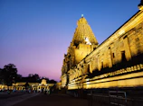 A historic temple glowing warmly in the golden hour light with visitors admiring it.